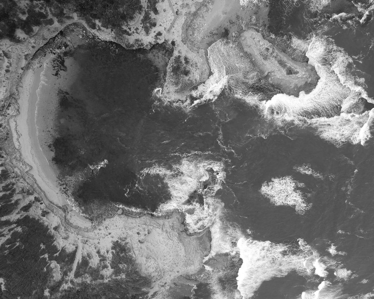 Black-and-white aerial view of waves breaking on a beach